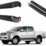 Vista principal de la pisadera trd para pick up toyota hilux vigo del 2006 al 2015 con una camioneta gris debajo