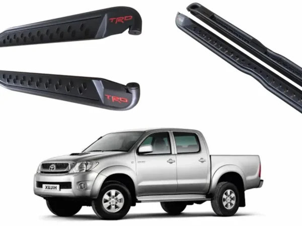 Vista principal de la pisadera trd para pick up toyota hilux vigo del 2006 al 2015 con una camioneta gris debajo